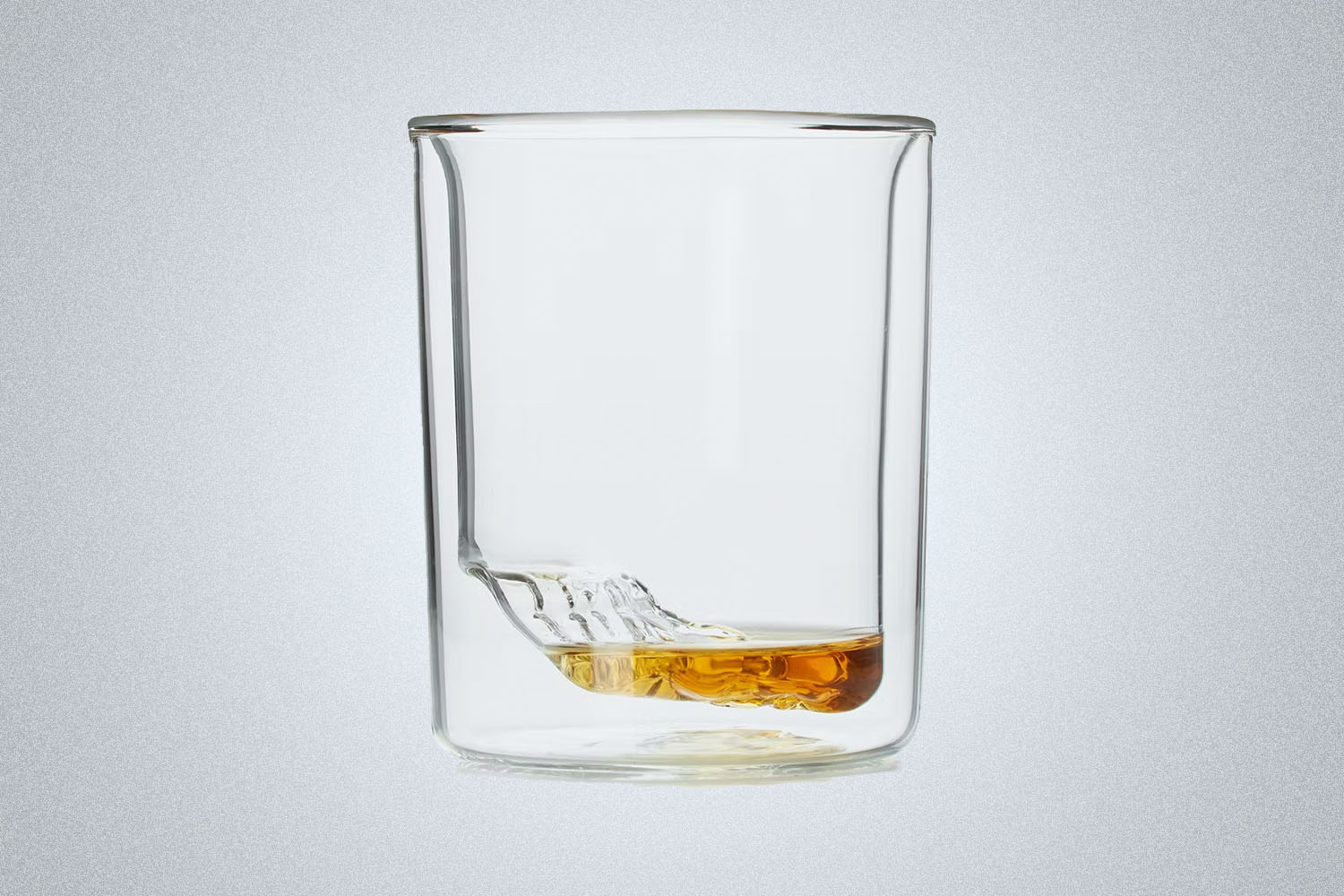 A whiskey glass with grand canyon carving on a grey background