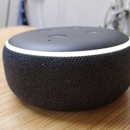 Close-up of Amazon Echo Dot third generation smart speaker with Alexa on light wooden surface,
