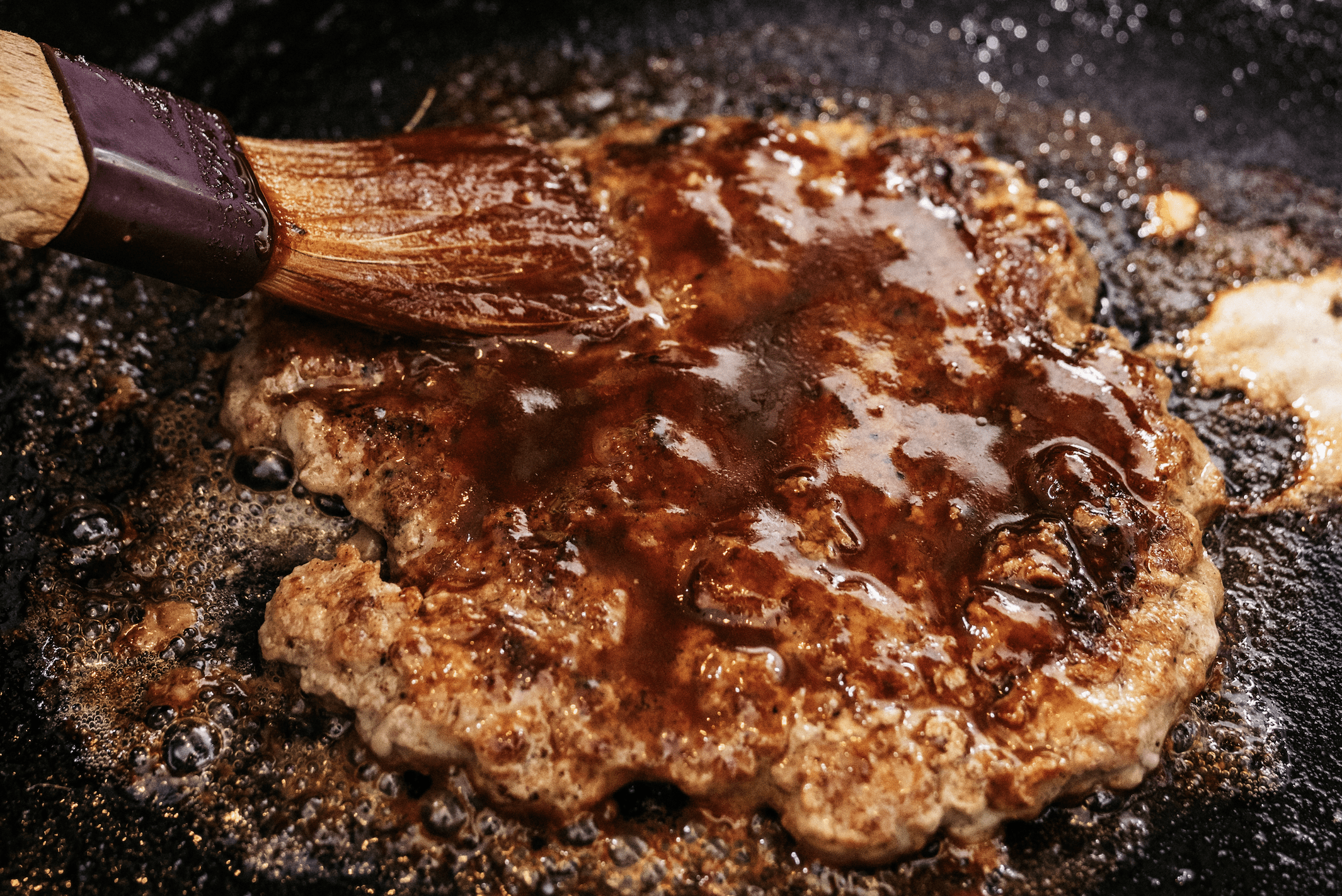Root beer BBQ sauce being spread on a burger