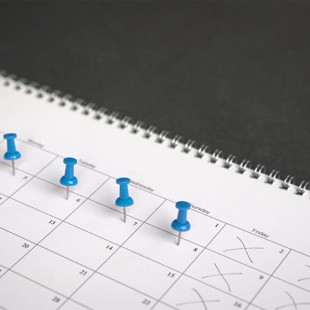 Blue pins on four days in a week on a calendar. Friday, Saturday and Sunday crossed out. Four day work week concept.