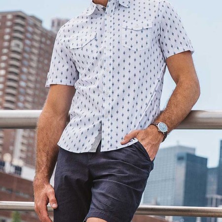 JACHS NY sitewide sale -- a man in JACHS shorts and a shirt leaning against a railing outside