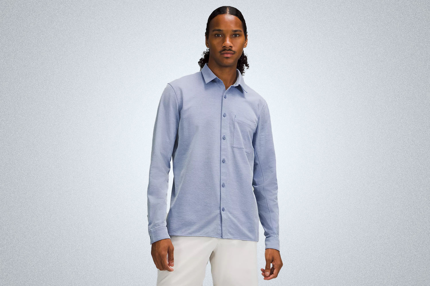 a model in a light blue button u pshirt from lululemon on a grey background