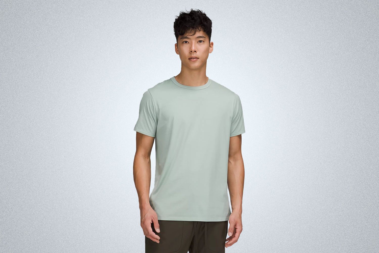 a model in a green lululemon shirt on a grey background