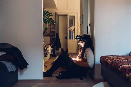 Woman with virtual reality headset sitting by wall at home. We look at a new report that suggests hate speech and virtual sexual assault are common in the metaverse, especially on Meta's (formerly Facebook) platforms.