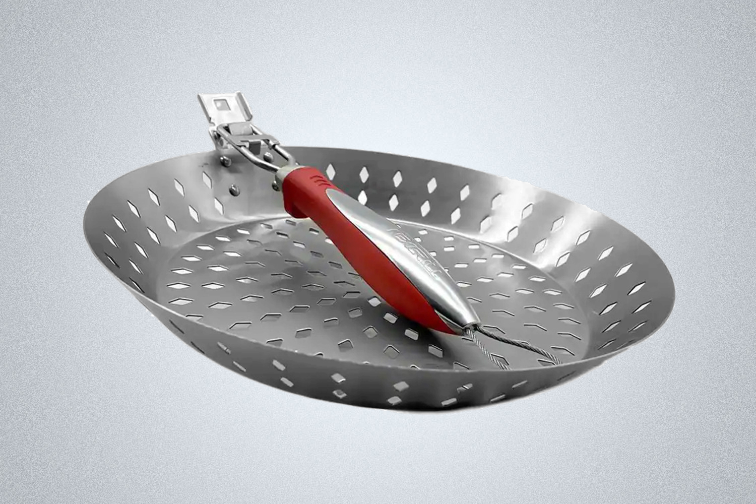 The Nexgrill Revelry Cooking Skillet, a grill pan with holes punched in the bottom, pictured with its handle folded down.