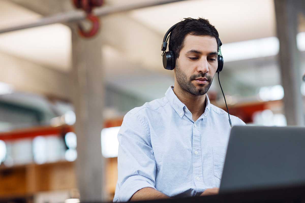 Stock photo of a man with headphones working in an office. The sound of your office can have negative or positive effects.
