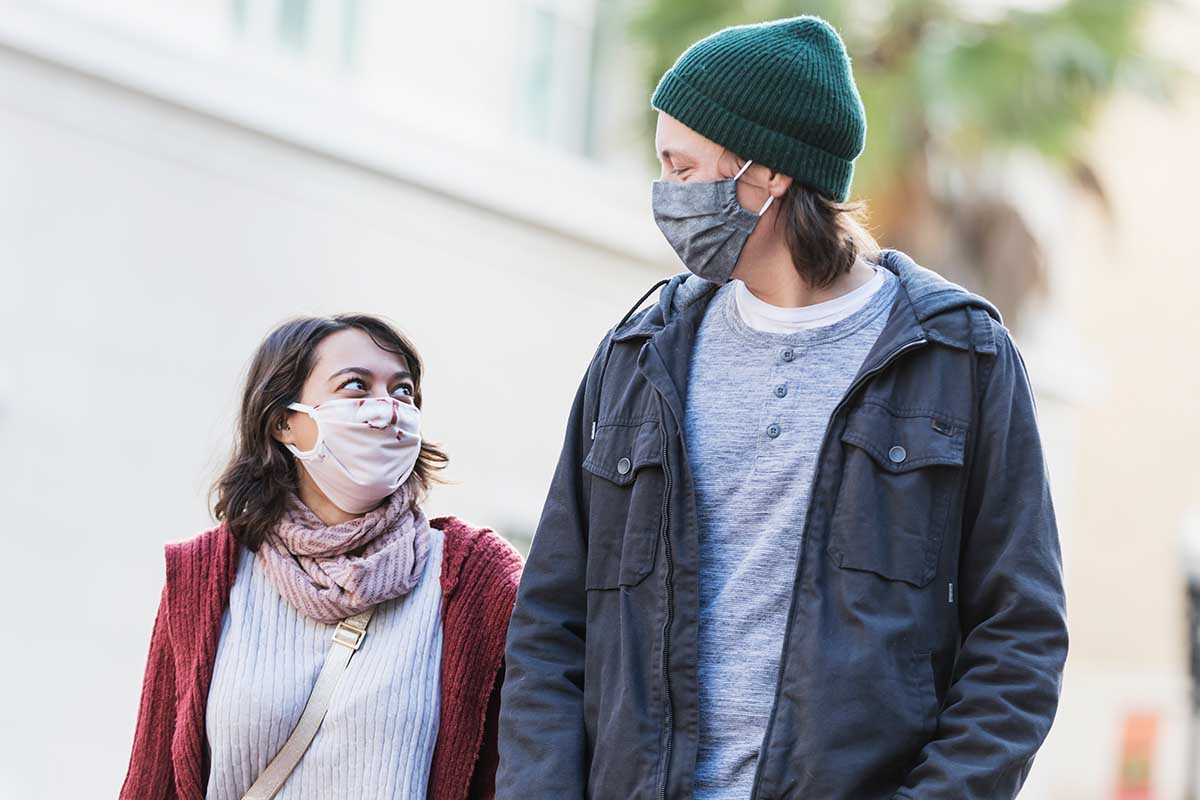 A shorter woman and taller man walking with masks. A new study suggests tall people may be more prone to certain health risks.