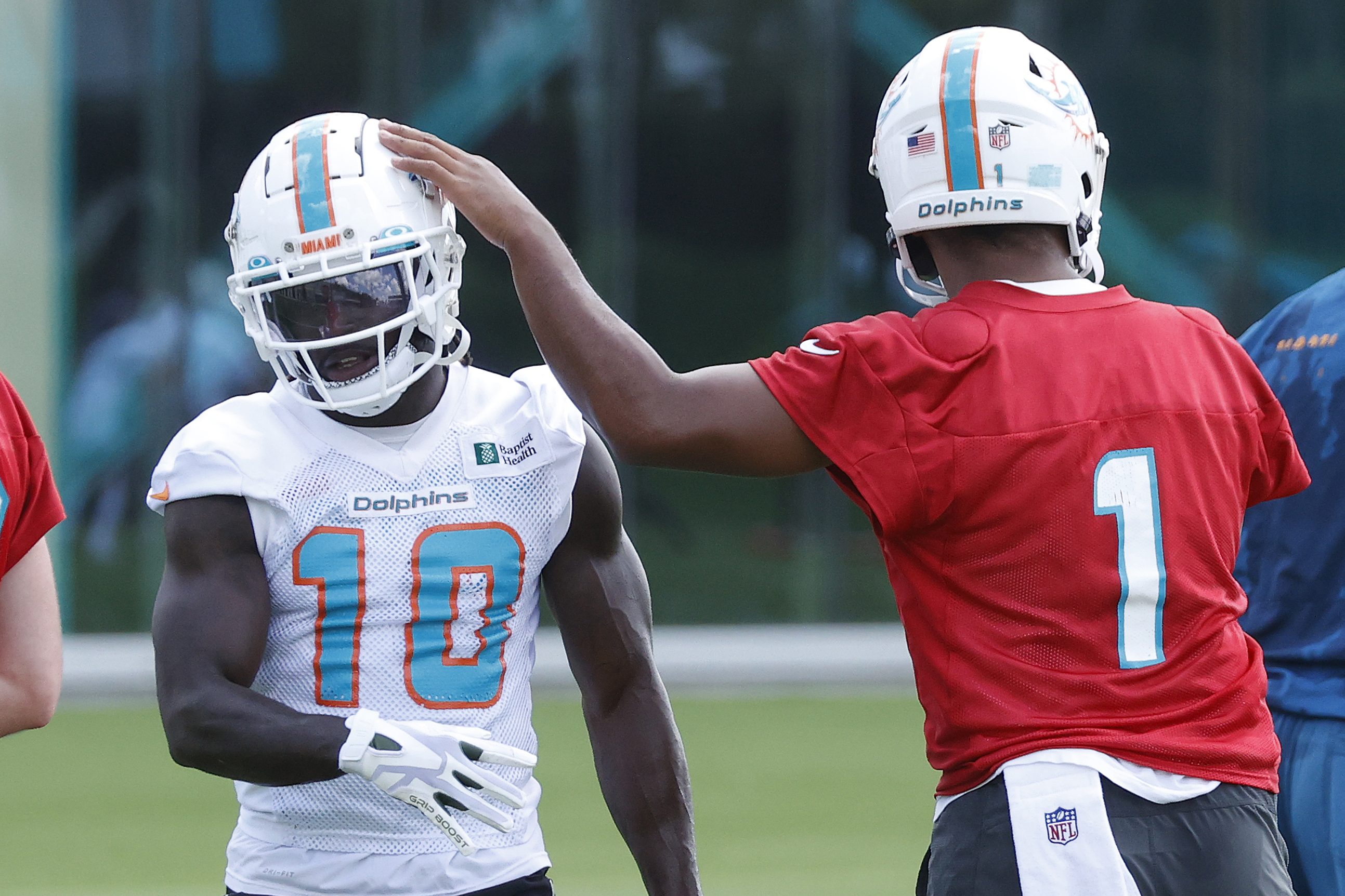 Tua Tagovailoa taps the helmet of Tyreek Hill of the Miami Dolphins