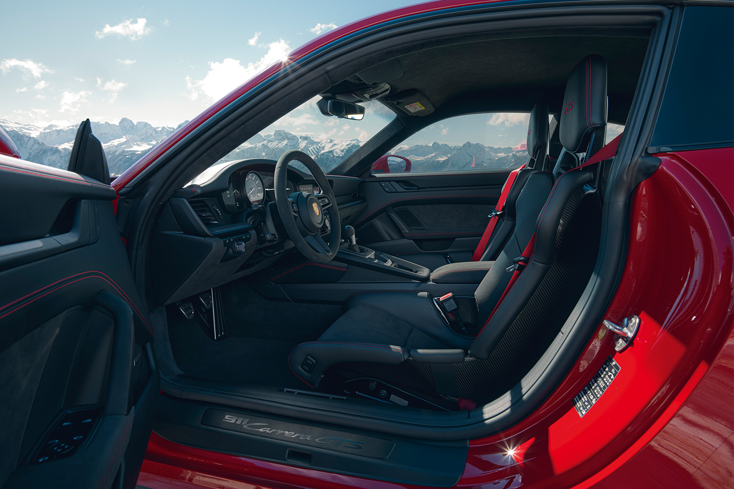 The front two seats of a 2022 Porsche 911 Carrera 4 GTS as seen from the open door of the driver's side