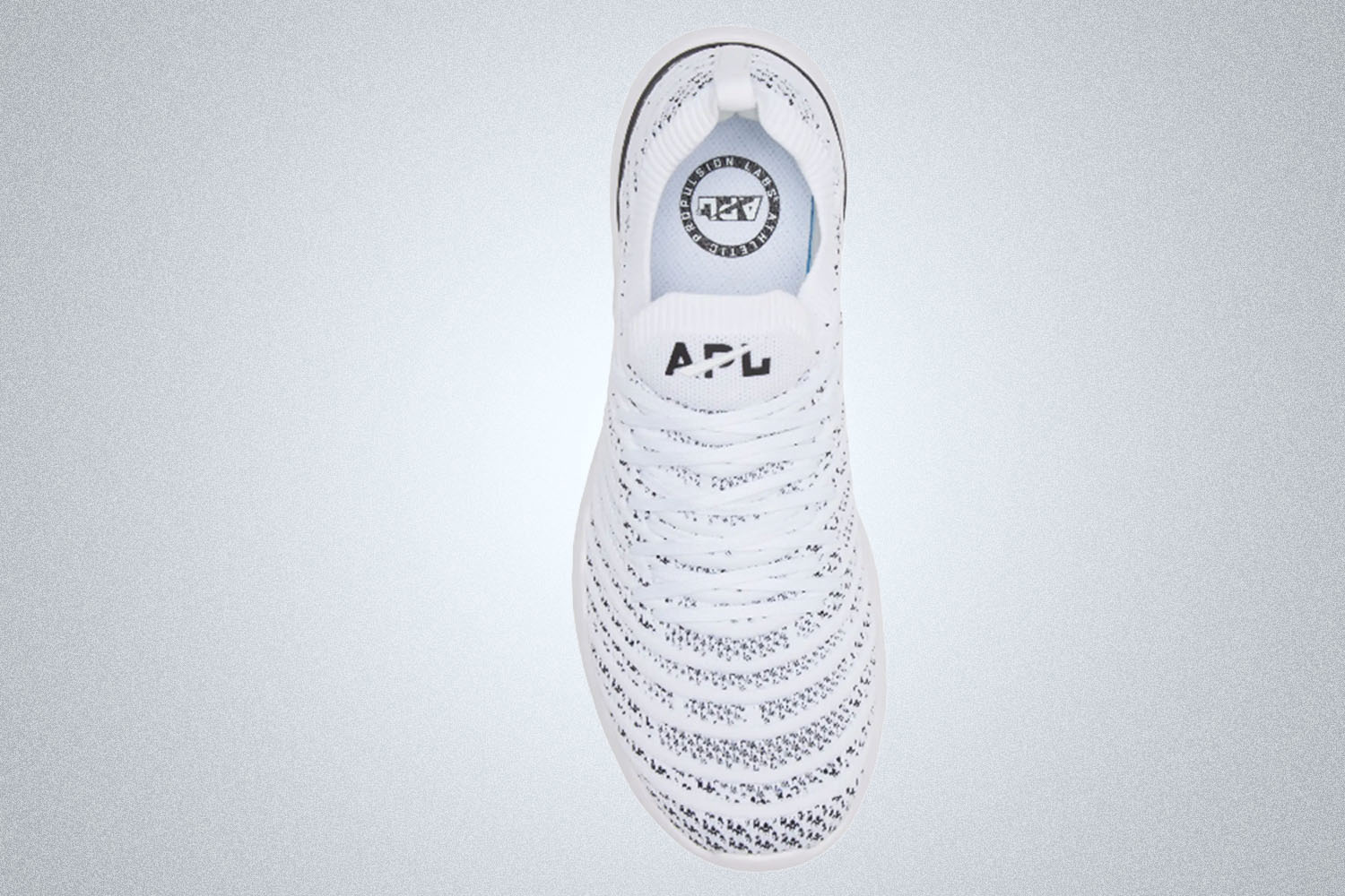 A white and black mesh APL sneaker on a grey background