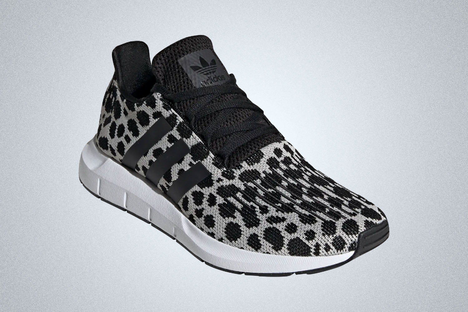a pair of animal-printed black and white Adidas sneakers on a grey background