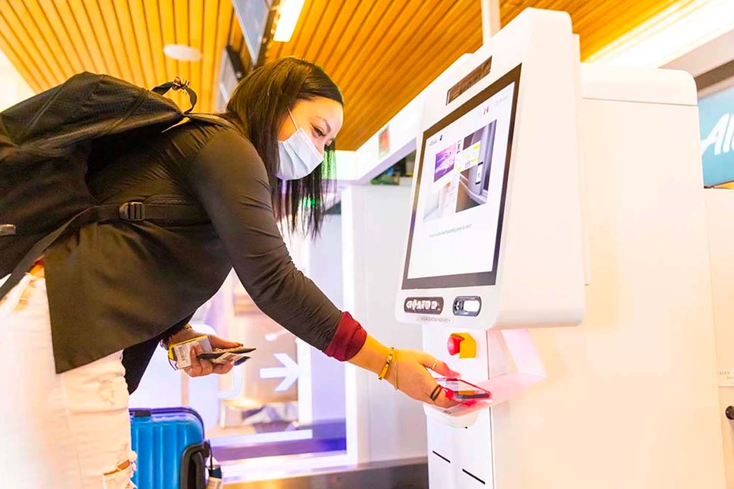 Passenger scanning an electric bag tag at a kiosk at Alaska Airlines check-in