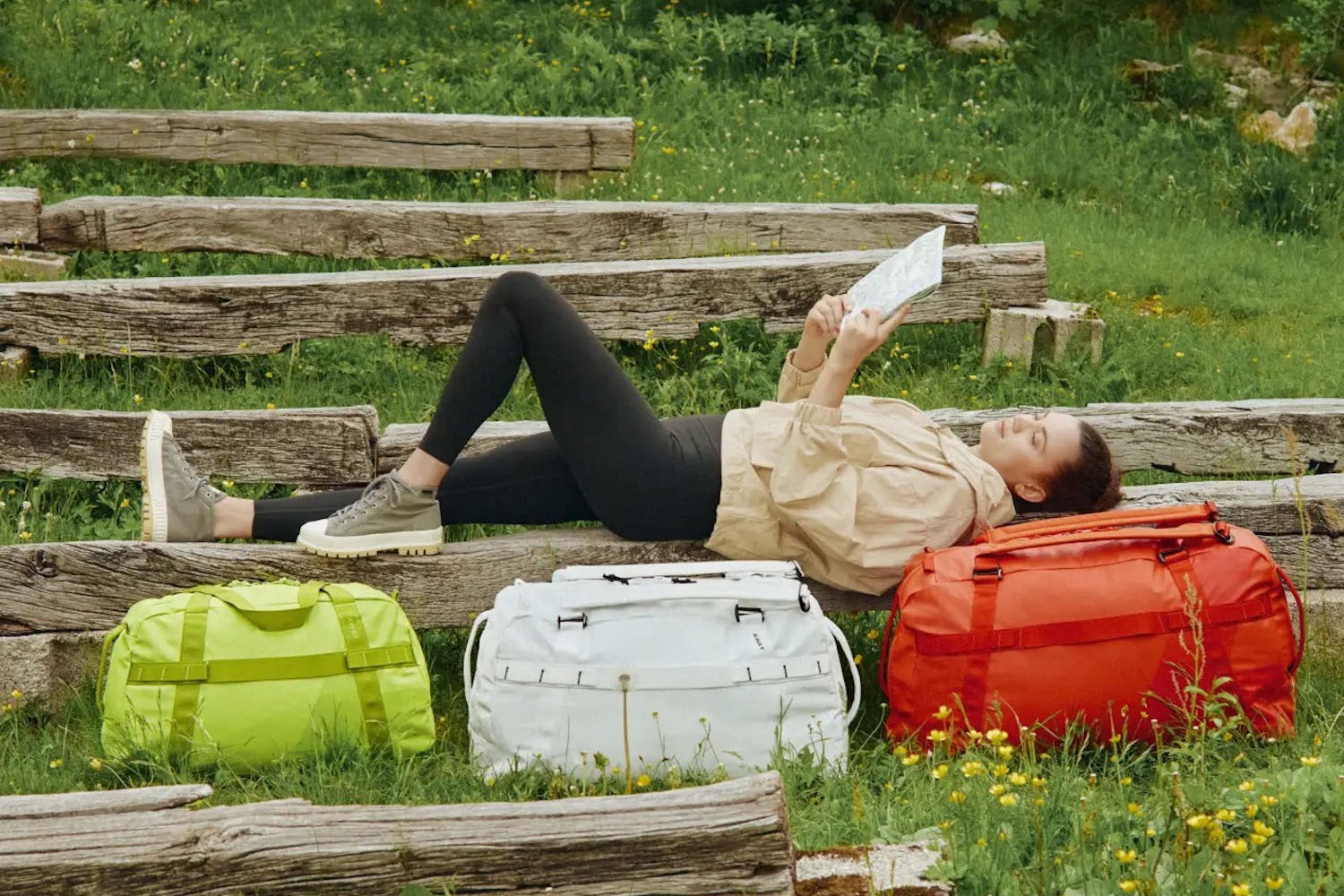 a model laying down reading a book surrounded by the Away FAR bags