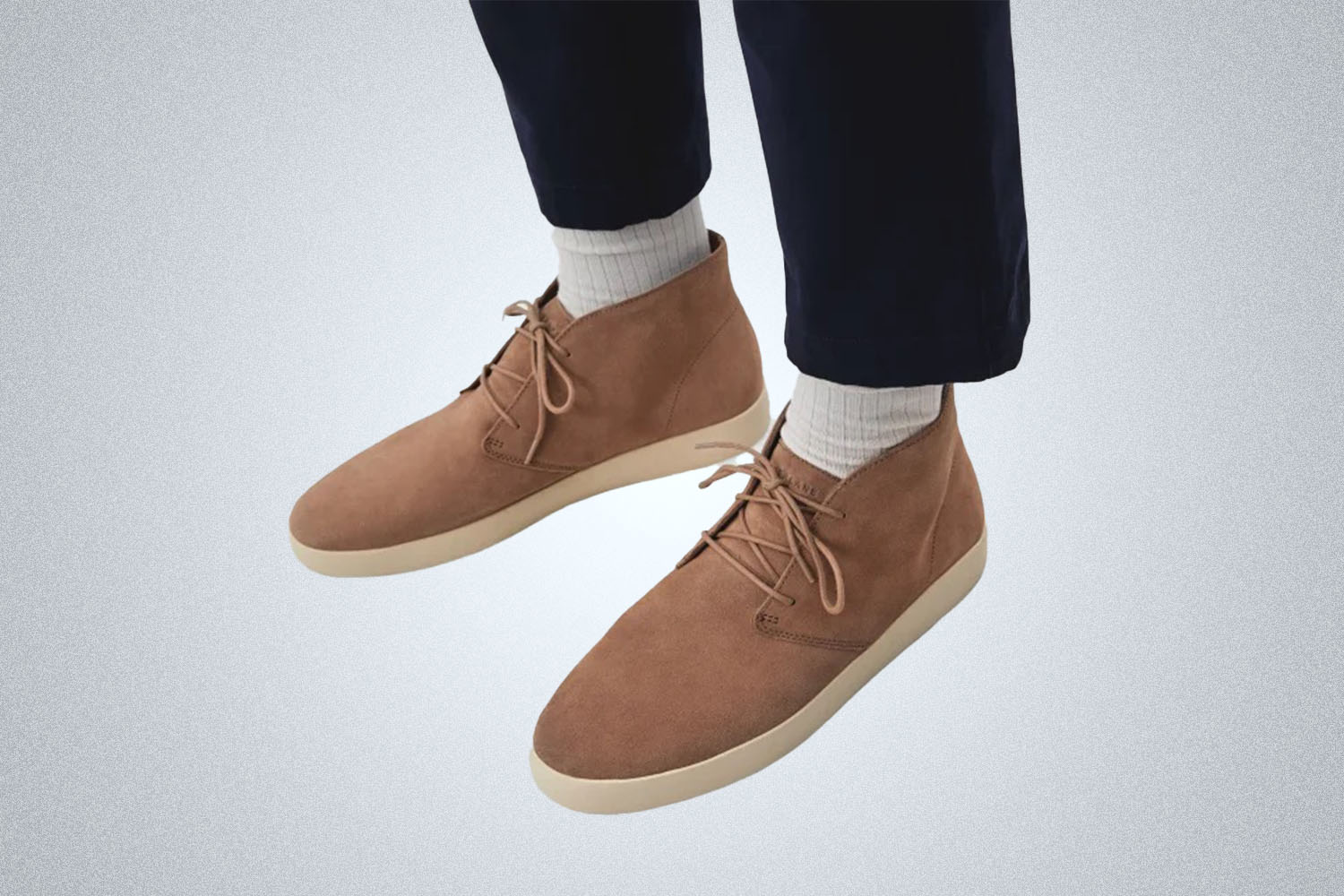a model against a grey background in a pair of the Everlane brown suede Everlane Chukka Desert Boot