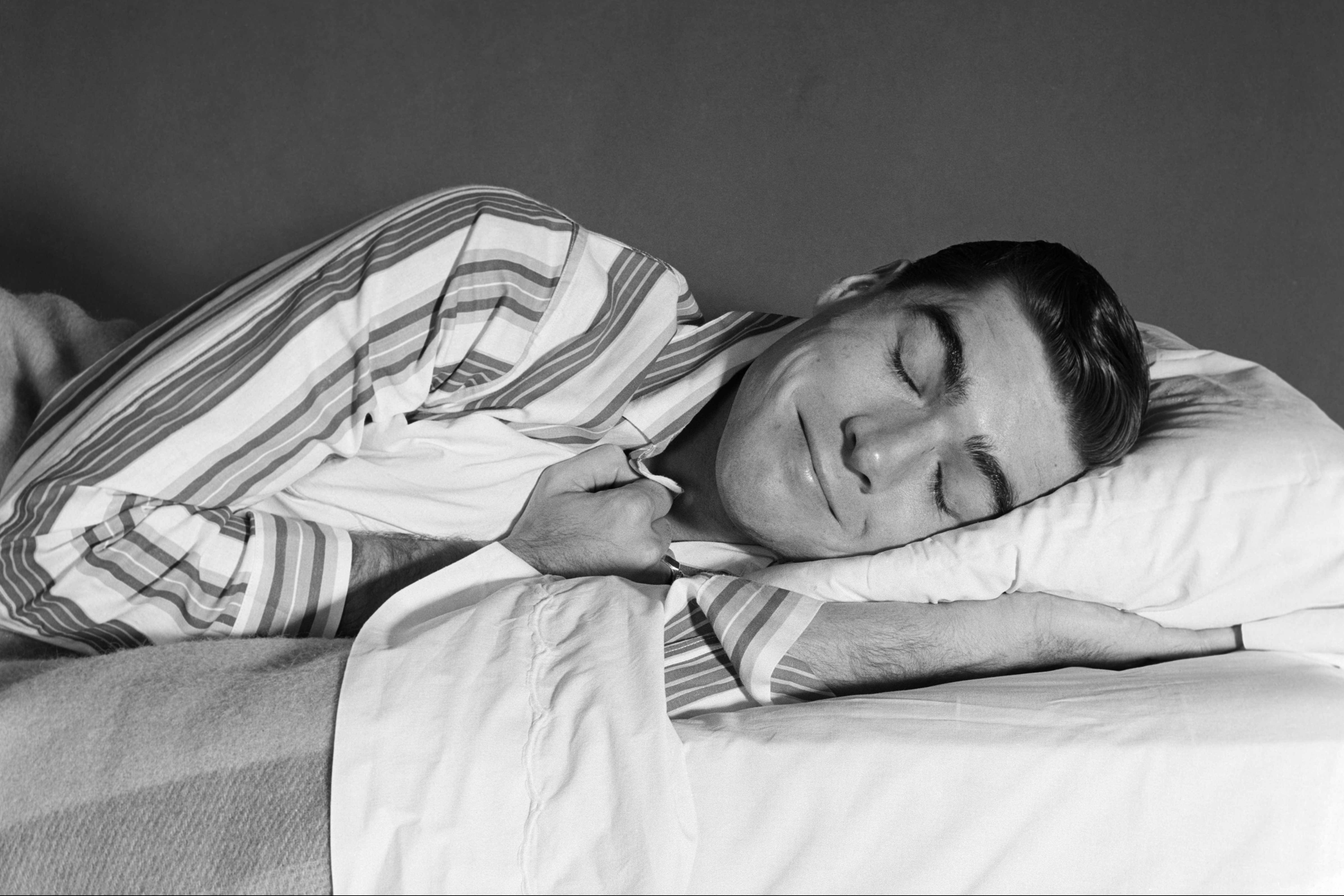 A man in pajamas naps in bed