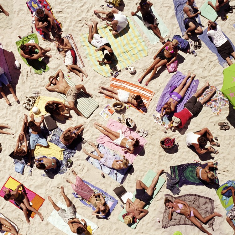 A crowd of sunbathers on the beach seen from a bird's-eye view
