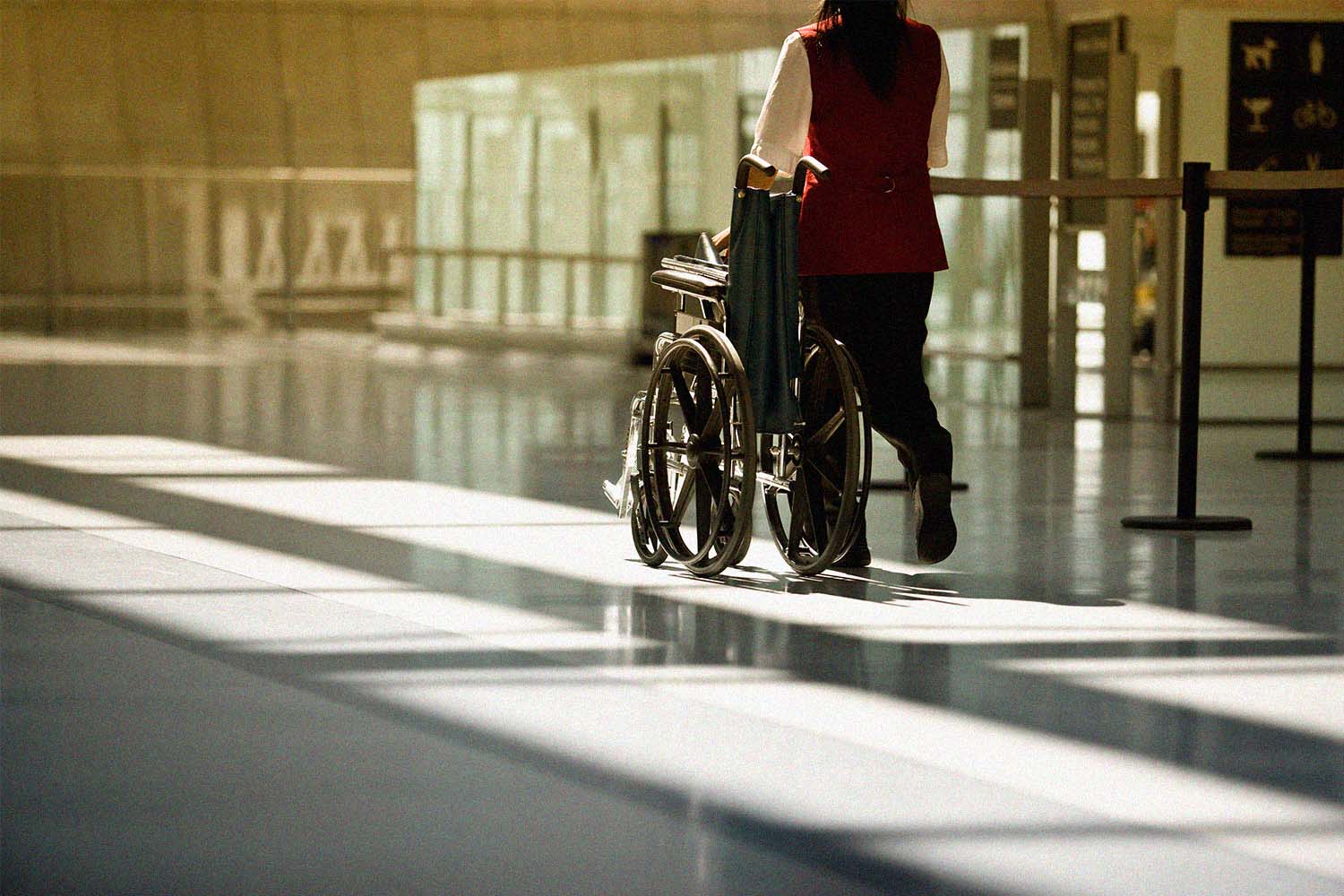 A woman pushes a wheelchair at the airport. The Heathrow CEO claims people are using a vile TikTok hack involving wheelchairs.