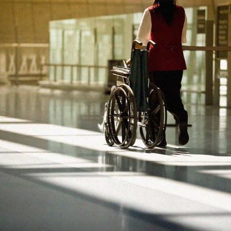 A woman pushes a wheelchair at the airport. The Heathrow CEO claims people are using a vile TikTok hack involving wheelchairs.