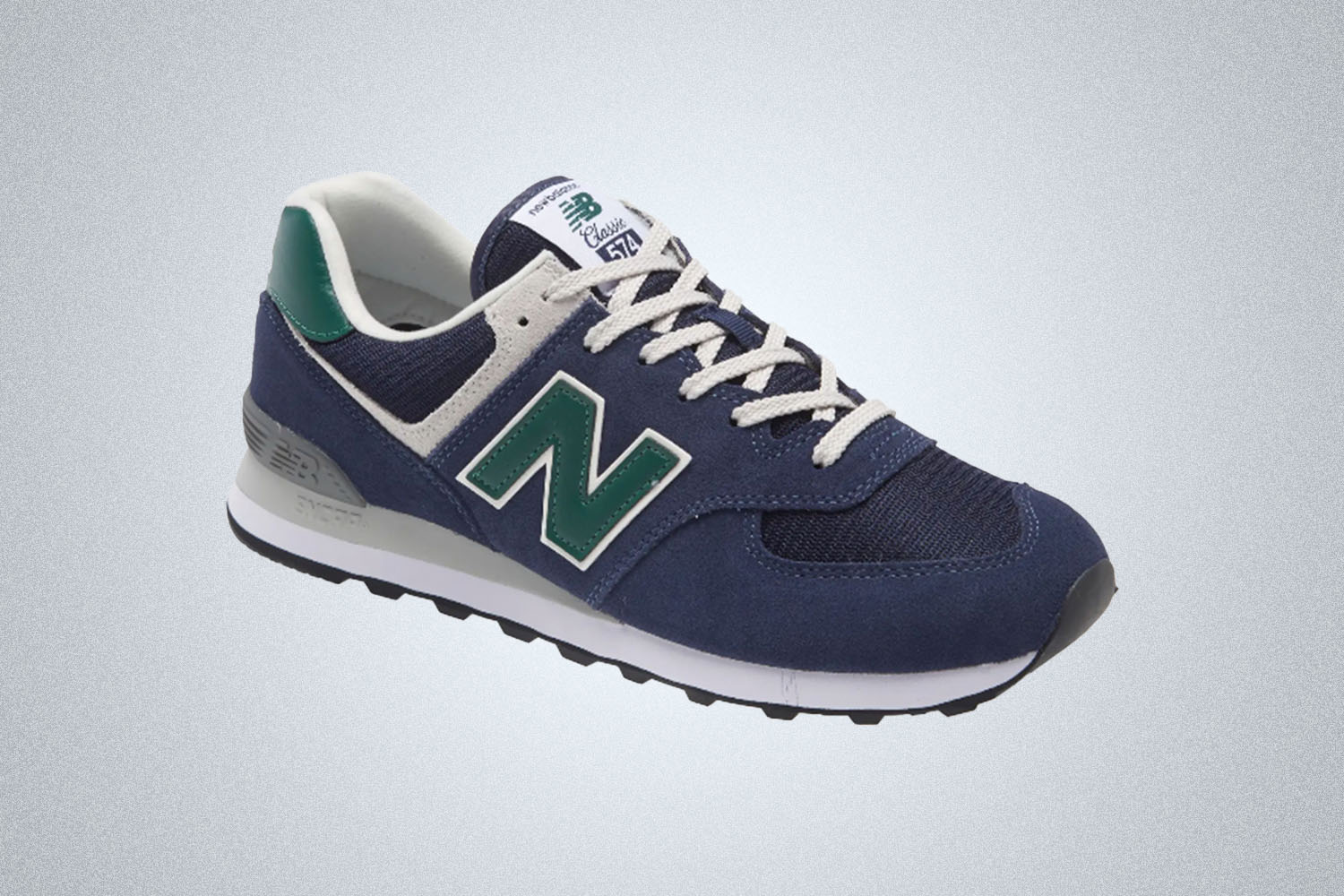a pair of New Balance blue and white and green 574 sneakers on a grey background