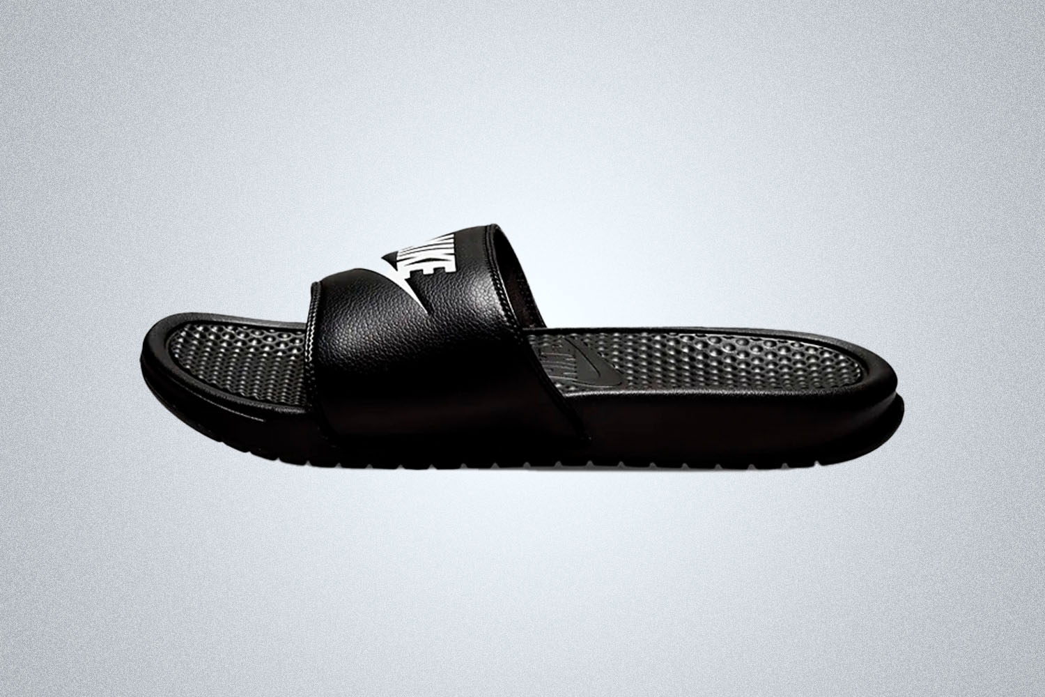 a pair of black Nike slides on a grey background
