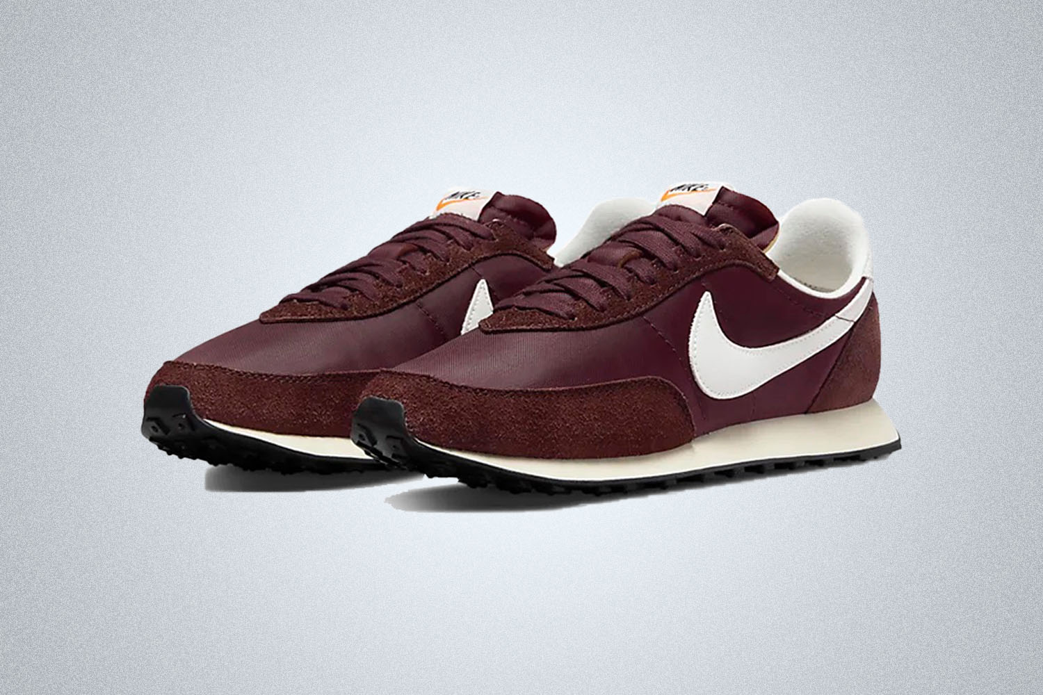 a pair of burgundy and white Nike retro sneakers on a grey background