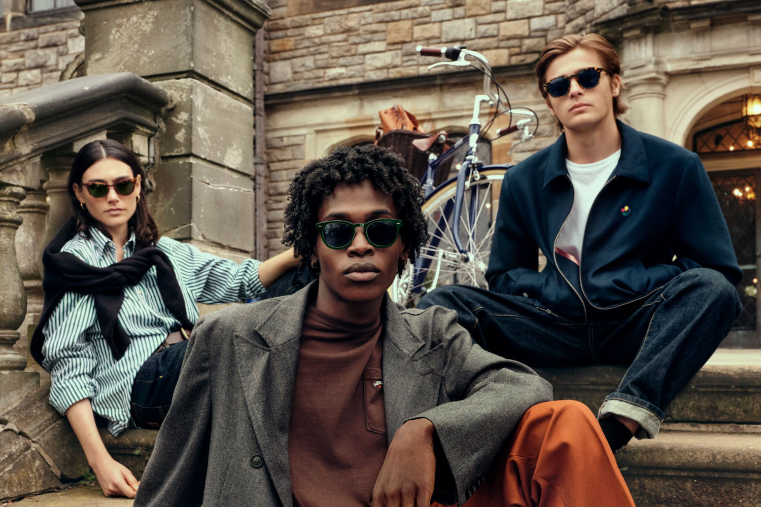 a trio of models in the Noah x Warby Parker eyewear against a brick background