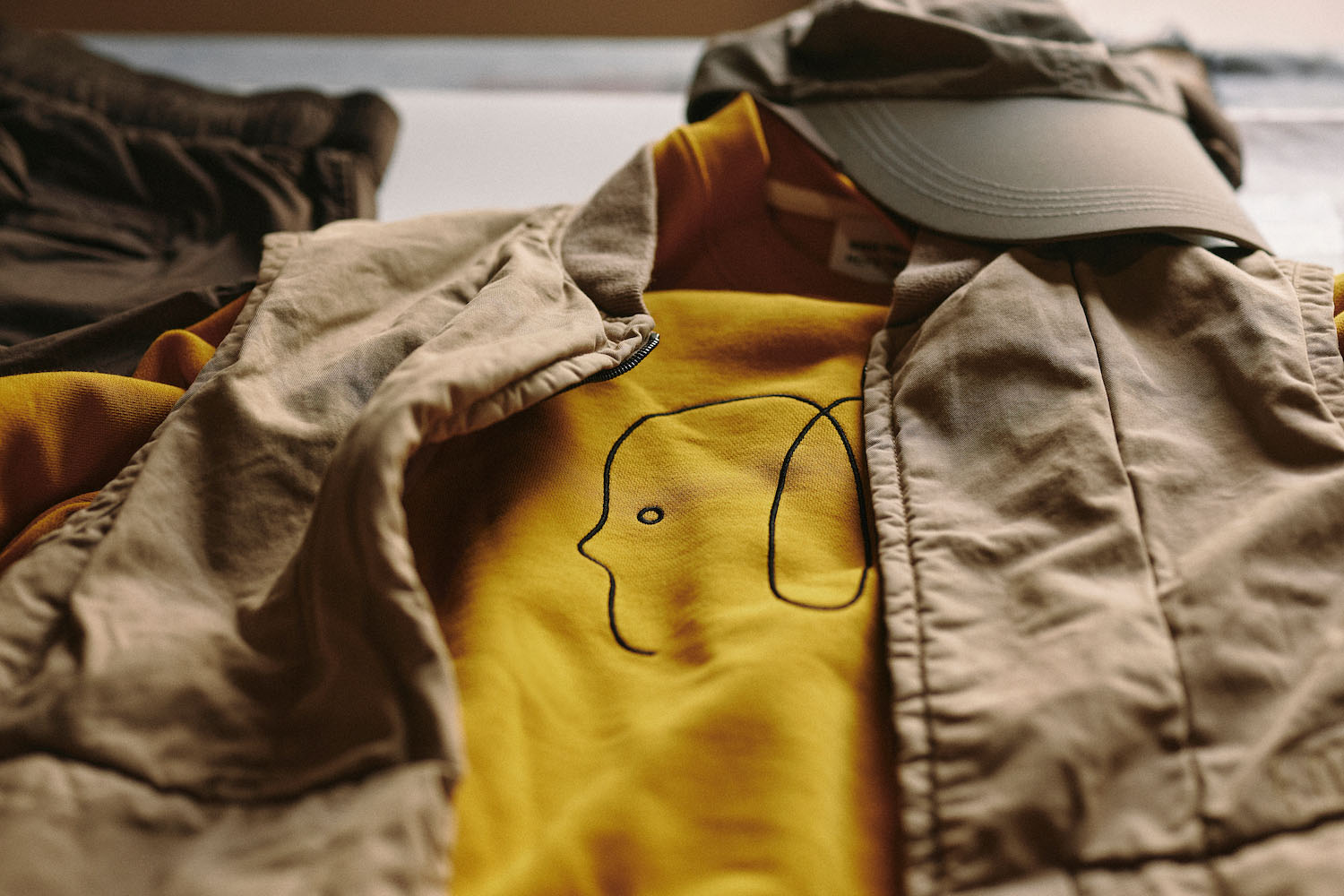 a product shot of a sweater, best and hat from the Norse Projects x Geoff McFetridge collection