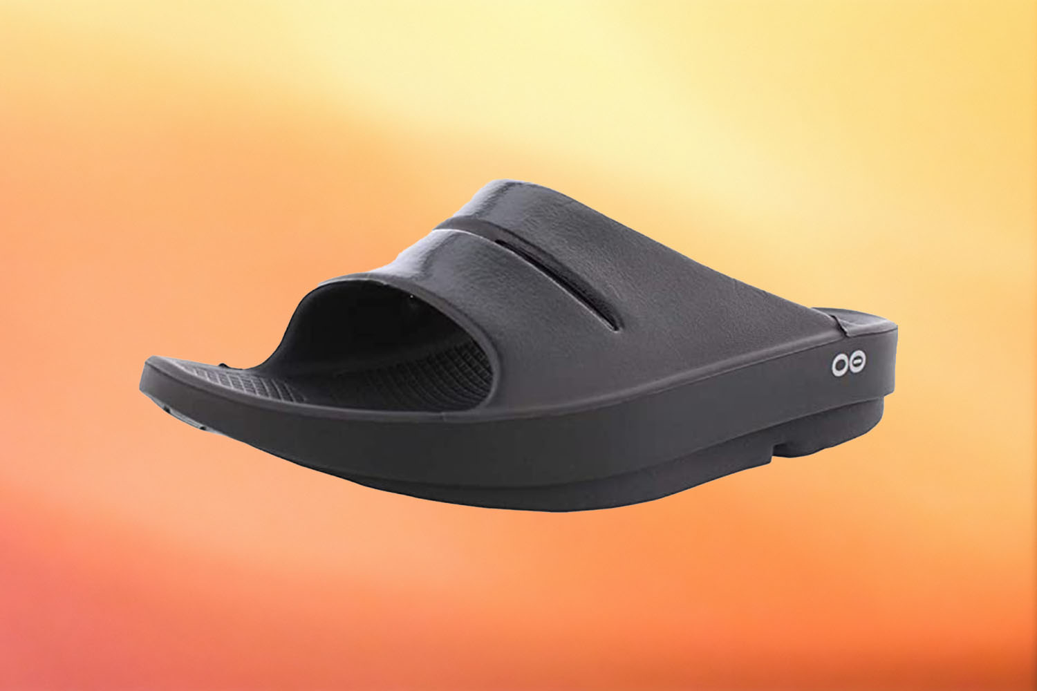a pair of black OOFOS slides on a yellow-orange gradient background