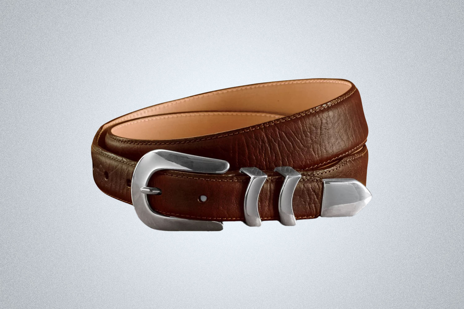 a silver tipped western leather belt from Orvis on a grey background