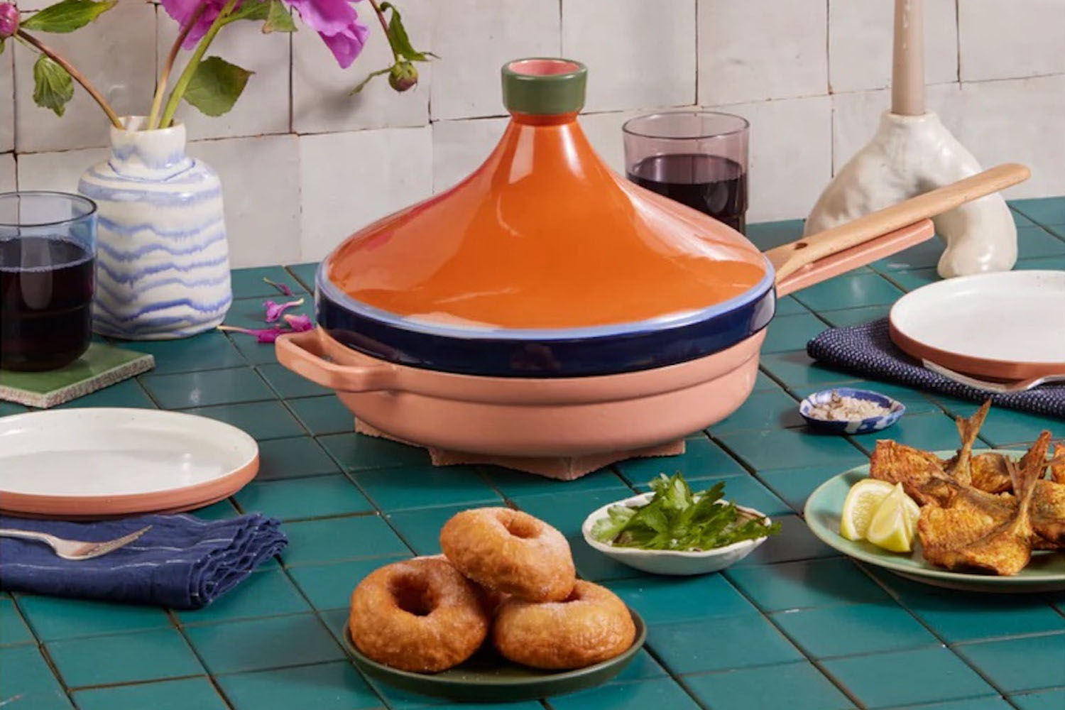 a orange Tagine from Our Place on a green table scape with food