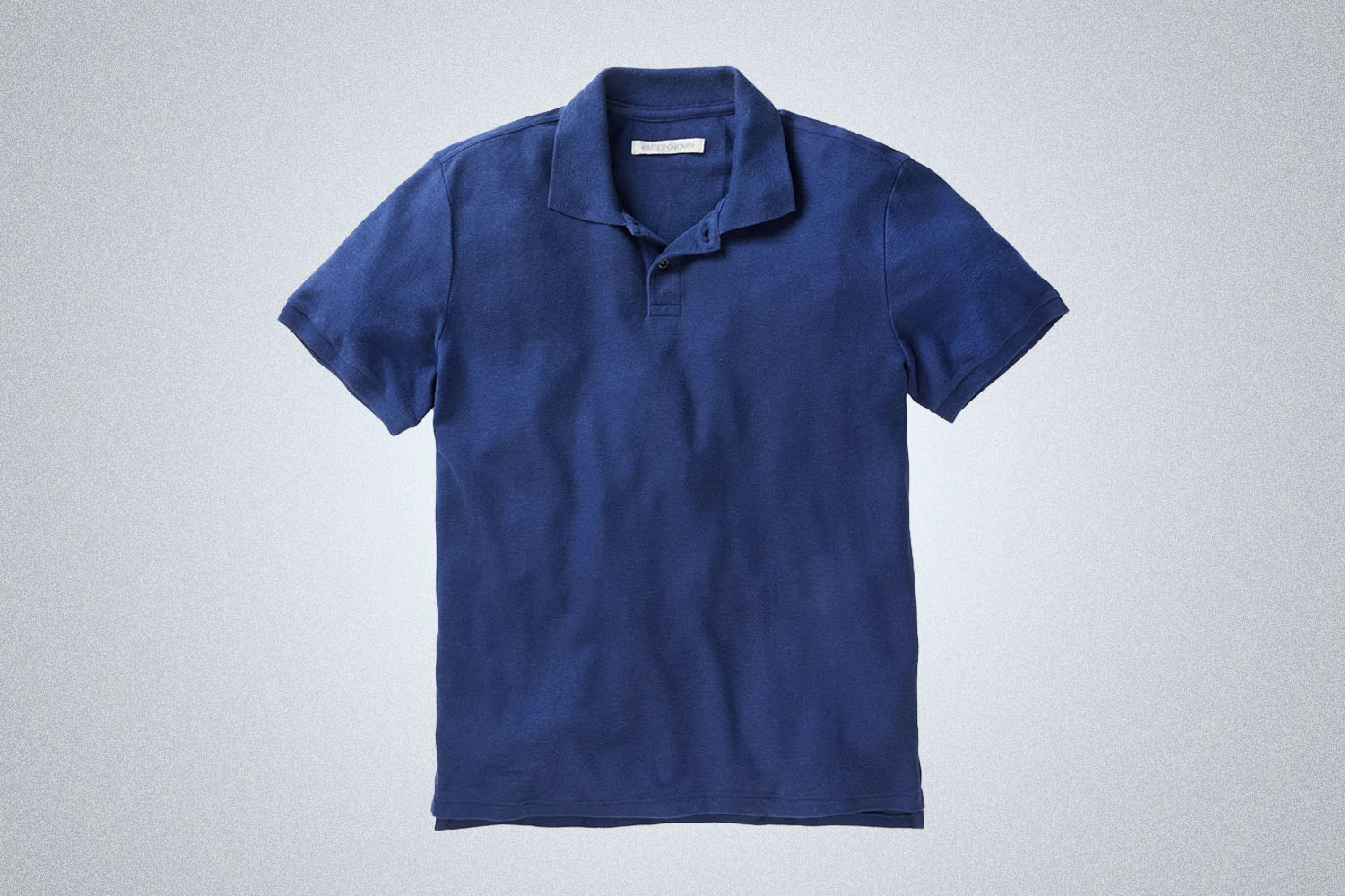 a blue polo from Outerknown on a grey background