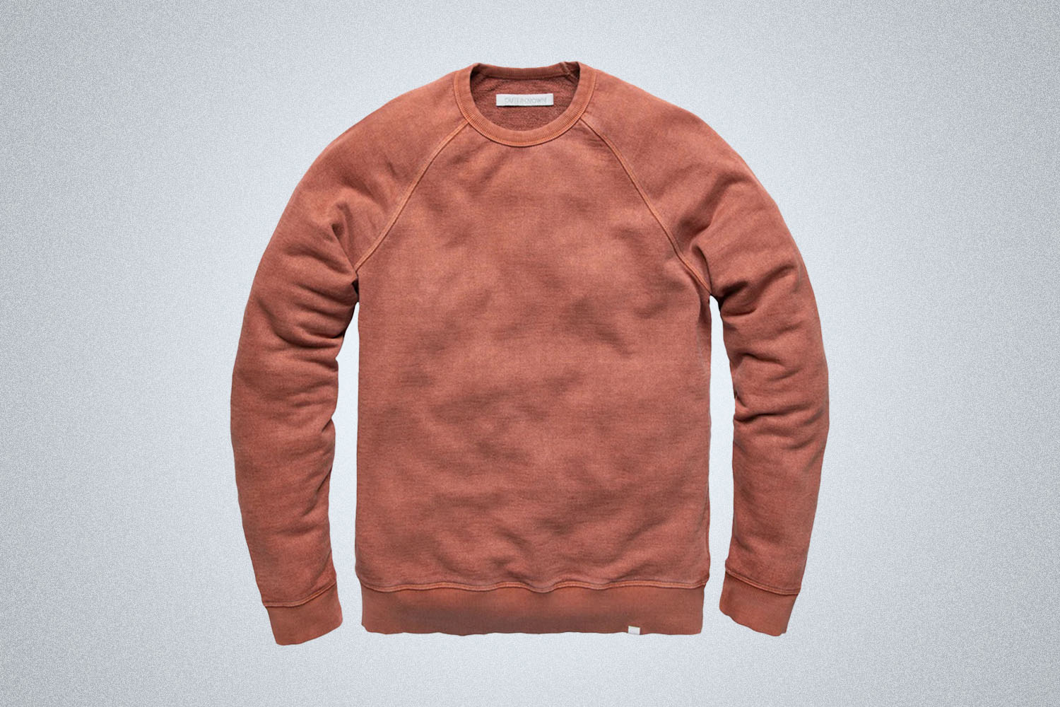a peach pullover sweater from Outerknown on a grey background