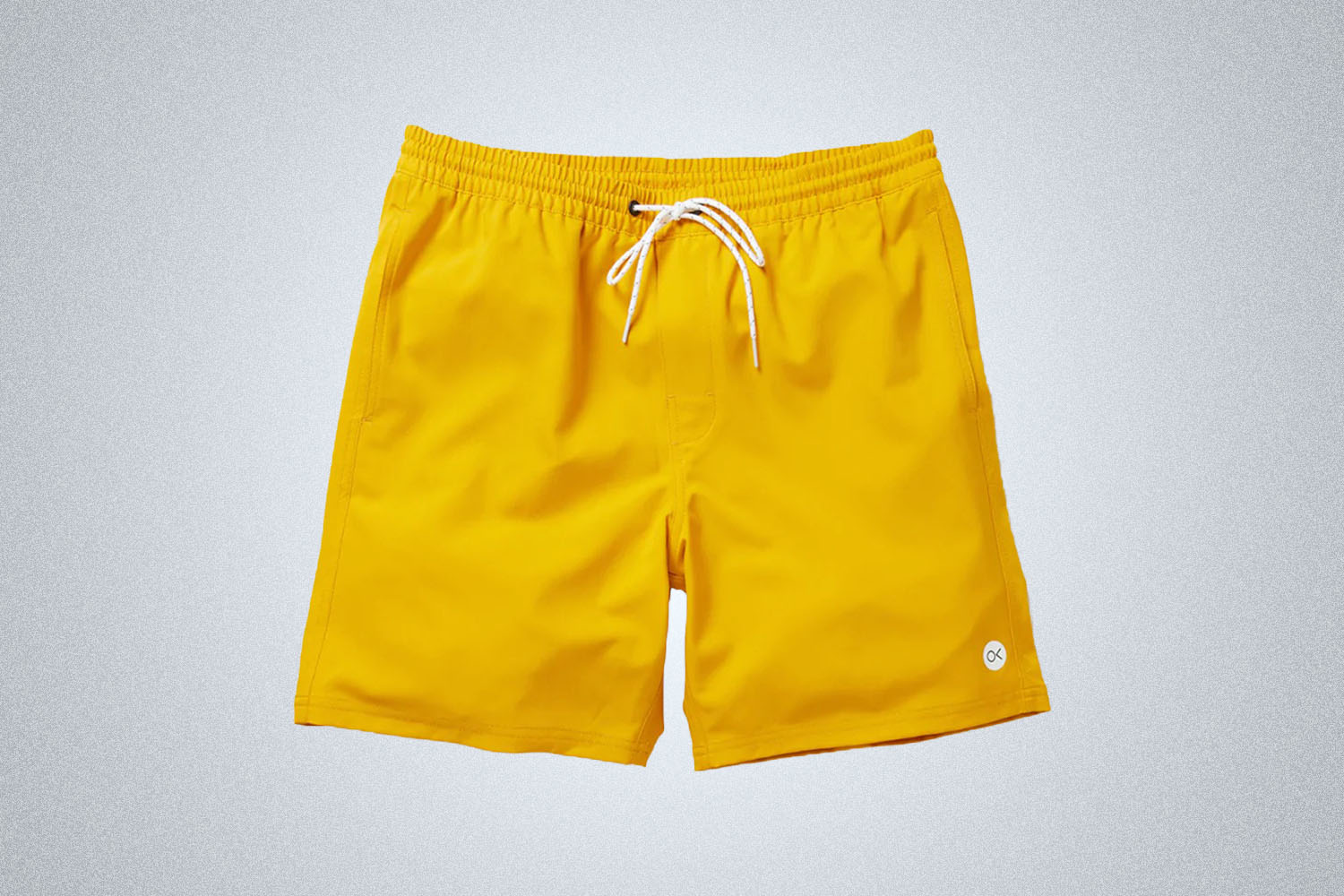 a pair of yellow volley shorts from Outerknown on a grey background