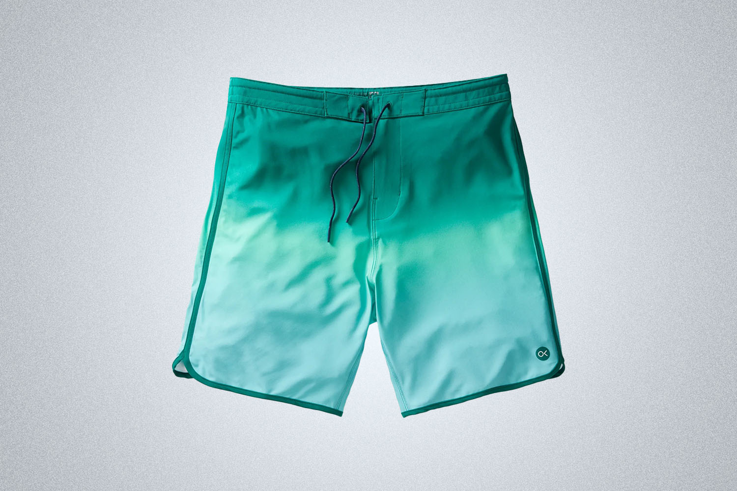 a pair of turquoise swim trunks from Outerknown on a grey background