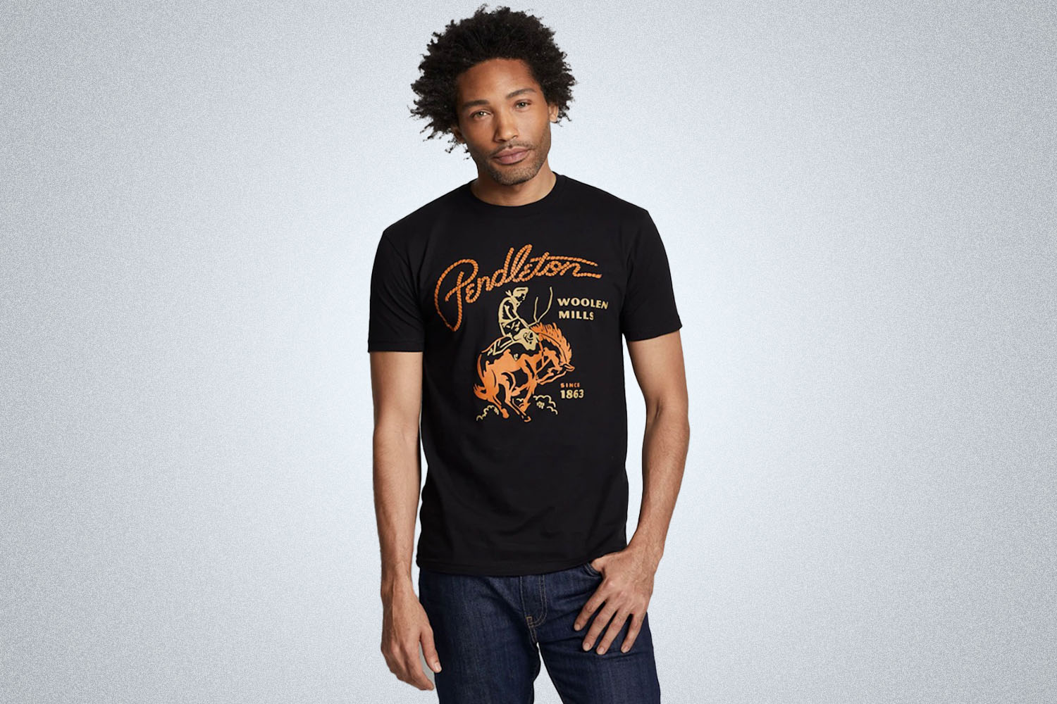 a model in a black graphic rodeo tee from  Pendleton on a grey background