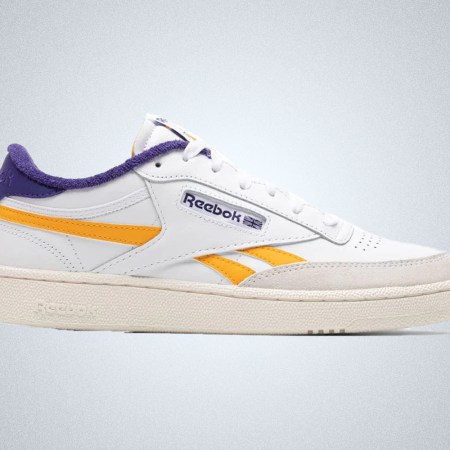a white shoe with yellow and purole detailing from Reebok on a grey background