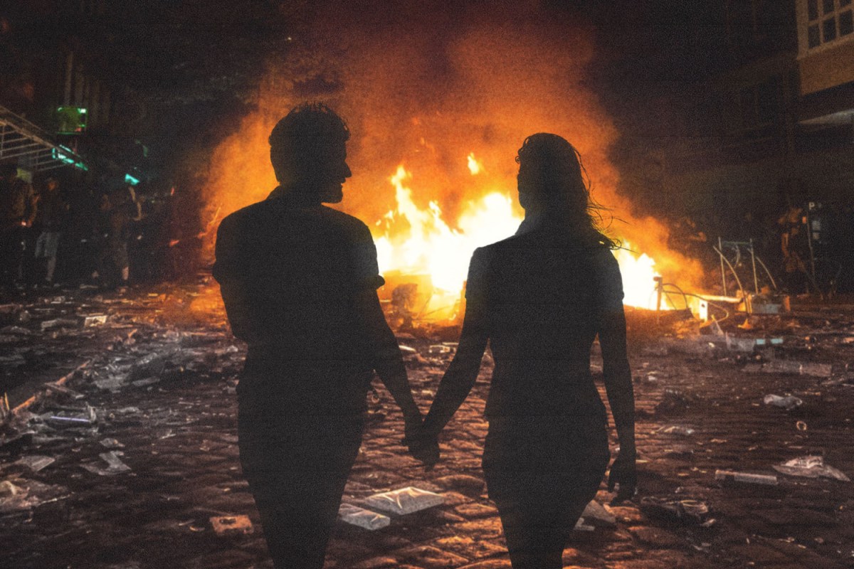 A couple holds hands in front of a massive open fire