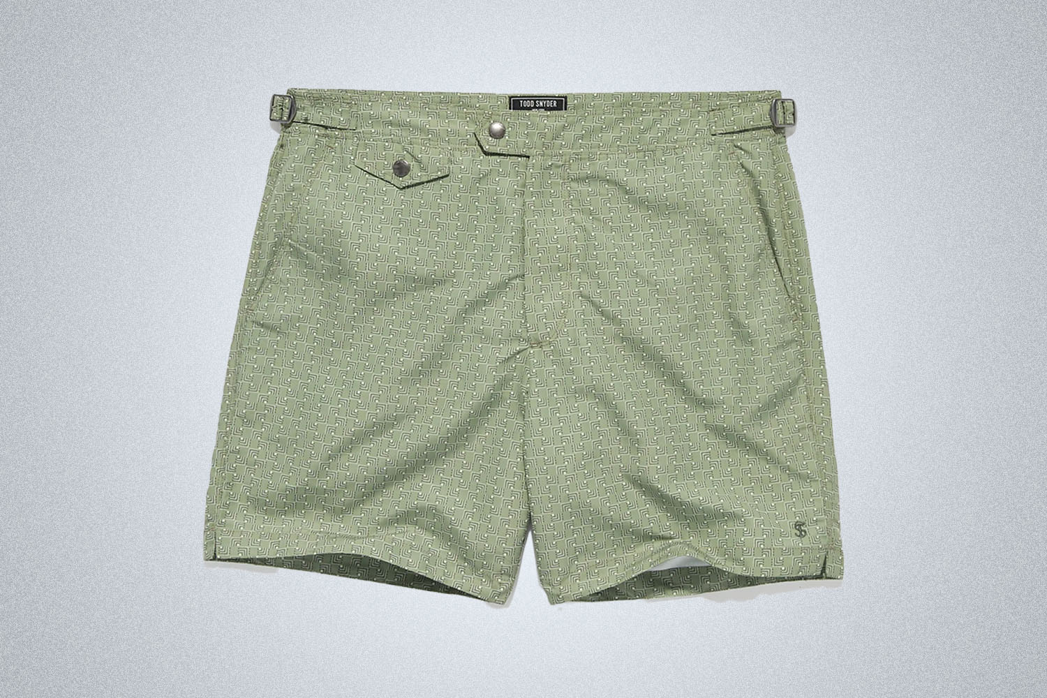 a pair of green patterned swim trunks from Todd Snyder on a grey background