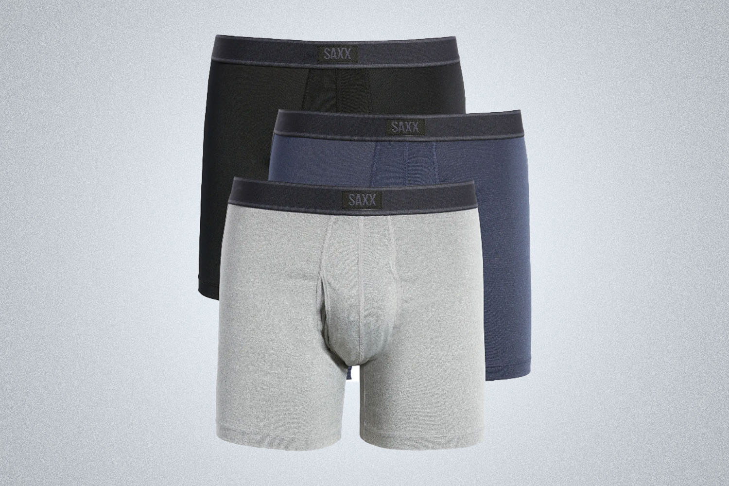 three pairs of overlayed boxers in black, blue and grey from SAXX on a grey background