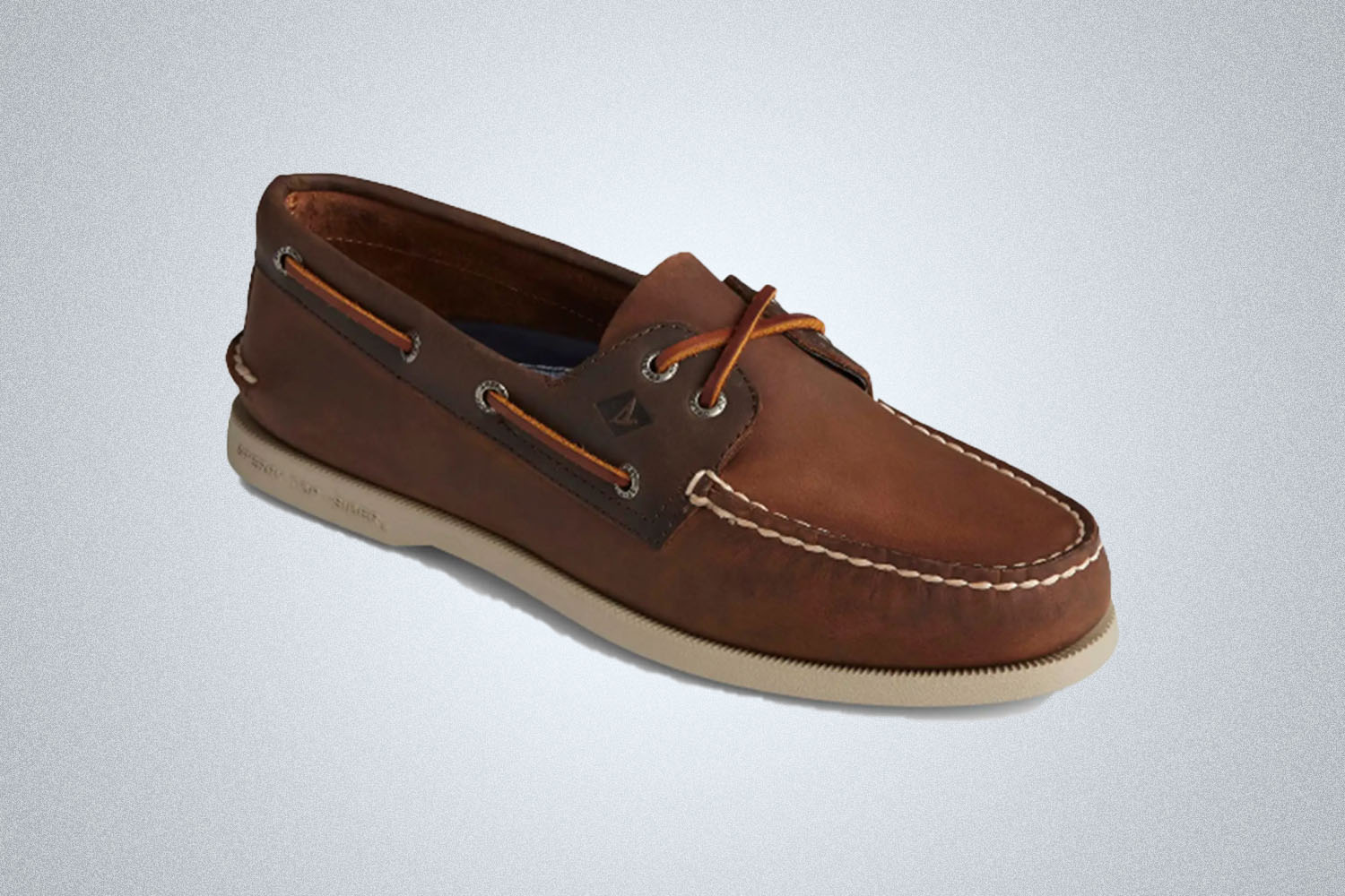 a brown leather boat shoe from Sperry on a grey background 