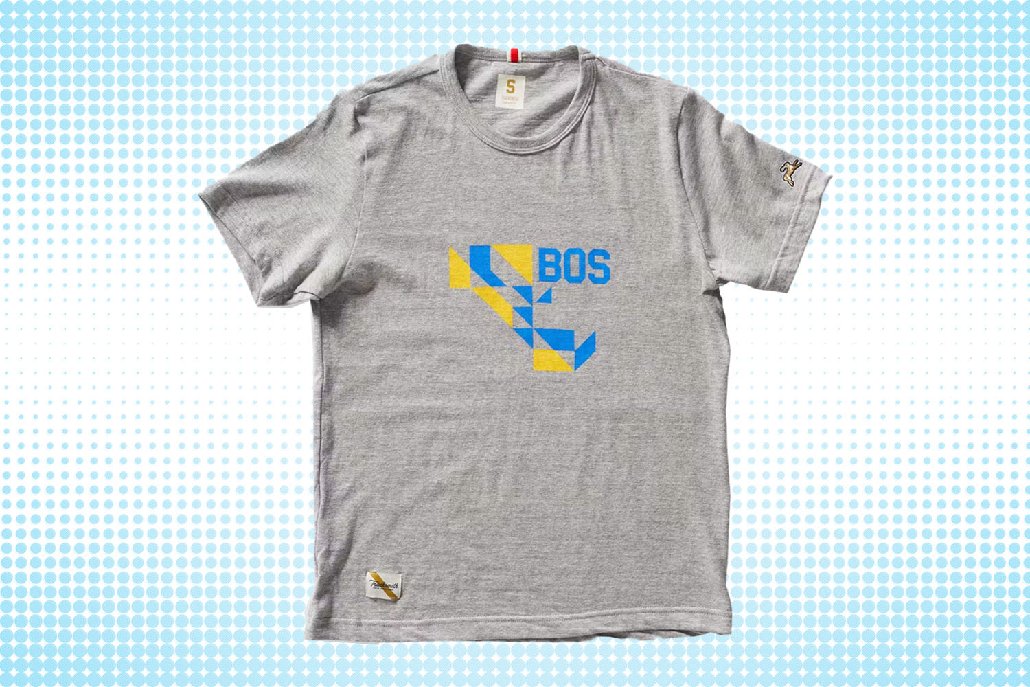 a grey short sleeve tee with "BOS" graphic from Tracksmith on a white and blue dotted background