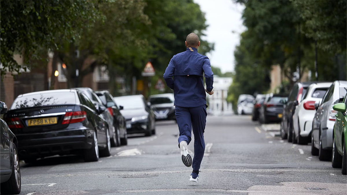 A model in Tracksmith clothing running in the middle of a street