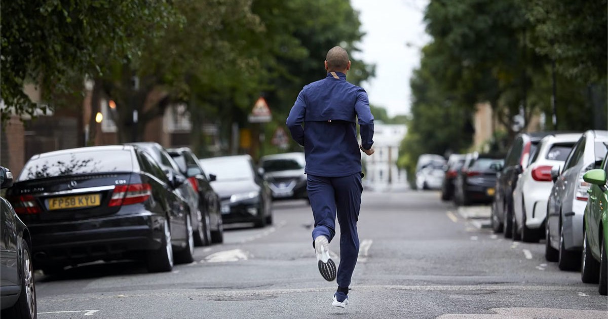 A model in Tracksmith clothing running in the middle of a street