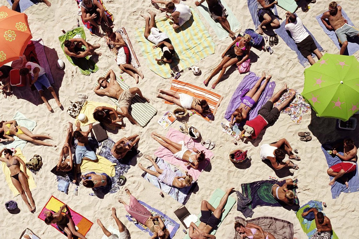 Crowd of people sunbathing on beach, over head view