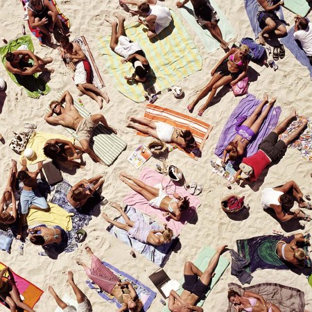 Crowd of people sunbathing on beach, over head view