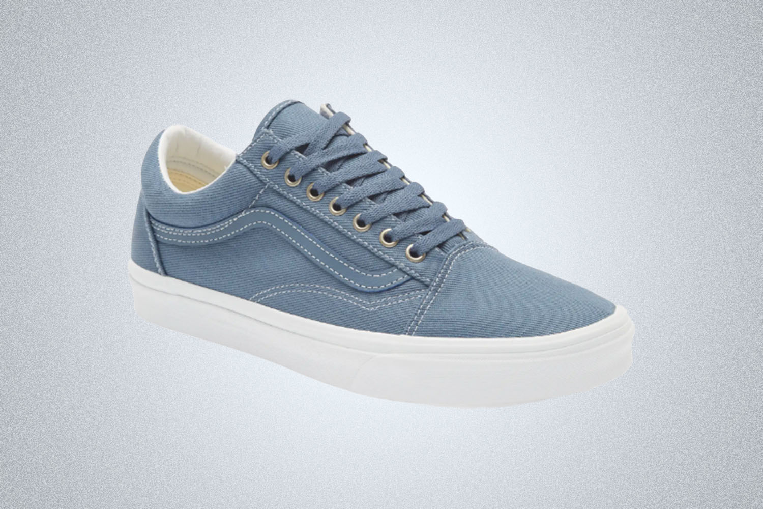 A pair of Vans Old Skool sneakers in a denim blue on a grey background