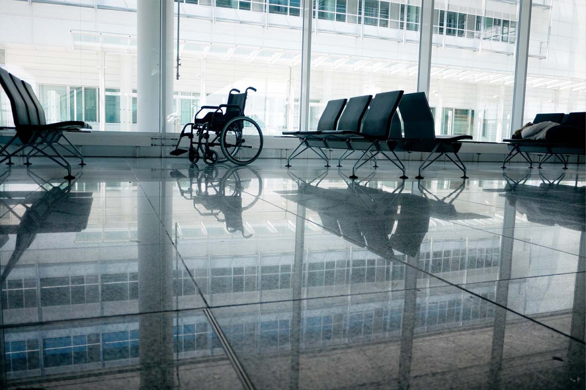 Wheelchair at the airport backlit with reflections on pavement.