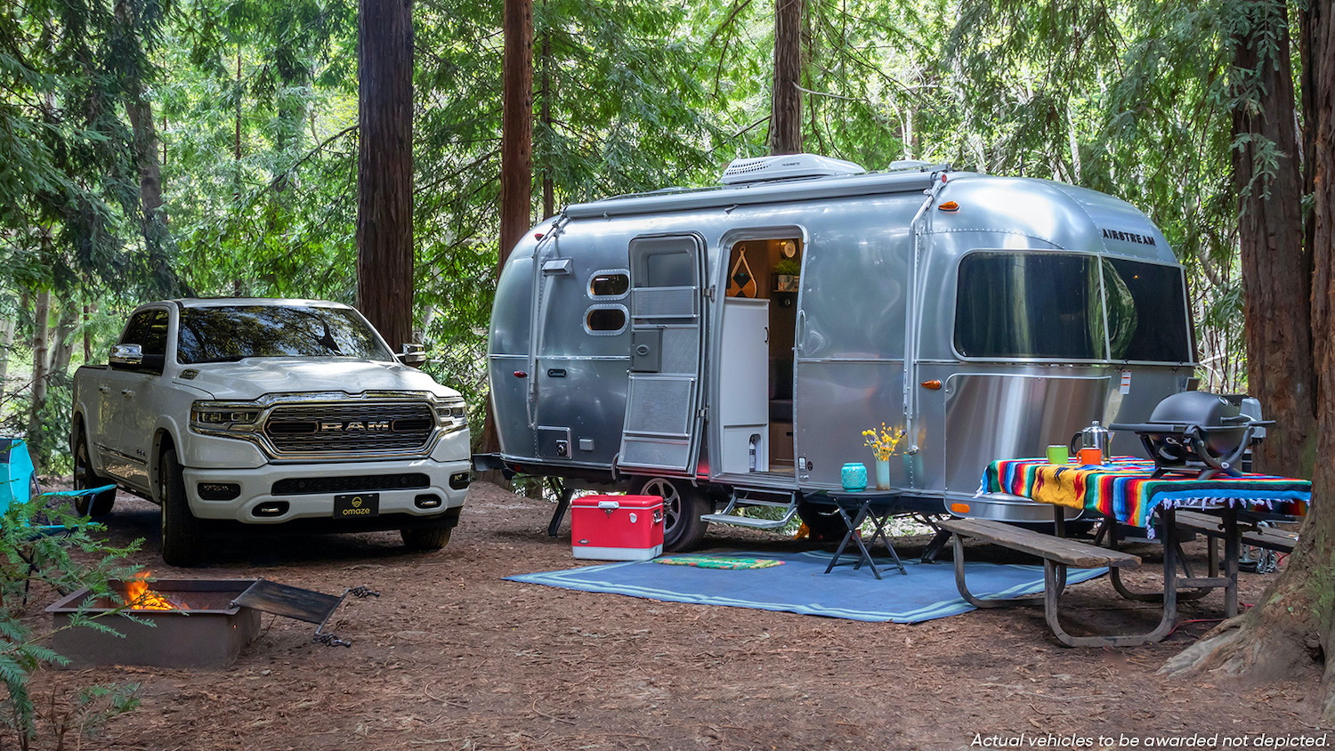 A Ram 1500 Limited pickup truck parked in the woods next to an Airstream Caravel 20FB, both of which Omaze is giving away