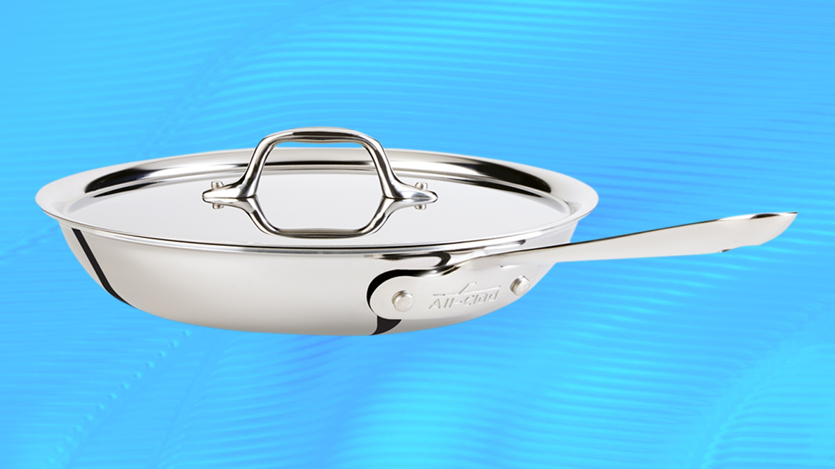 A stainless steel fry pan from All-Clad with a lid on a blue background