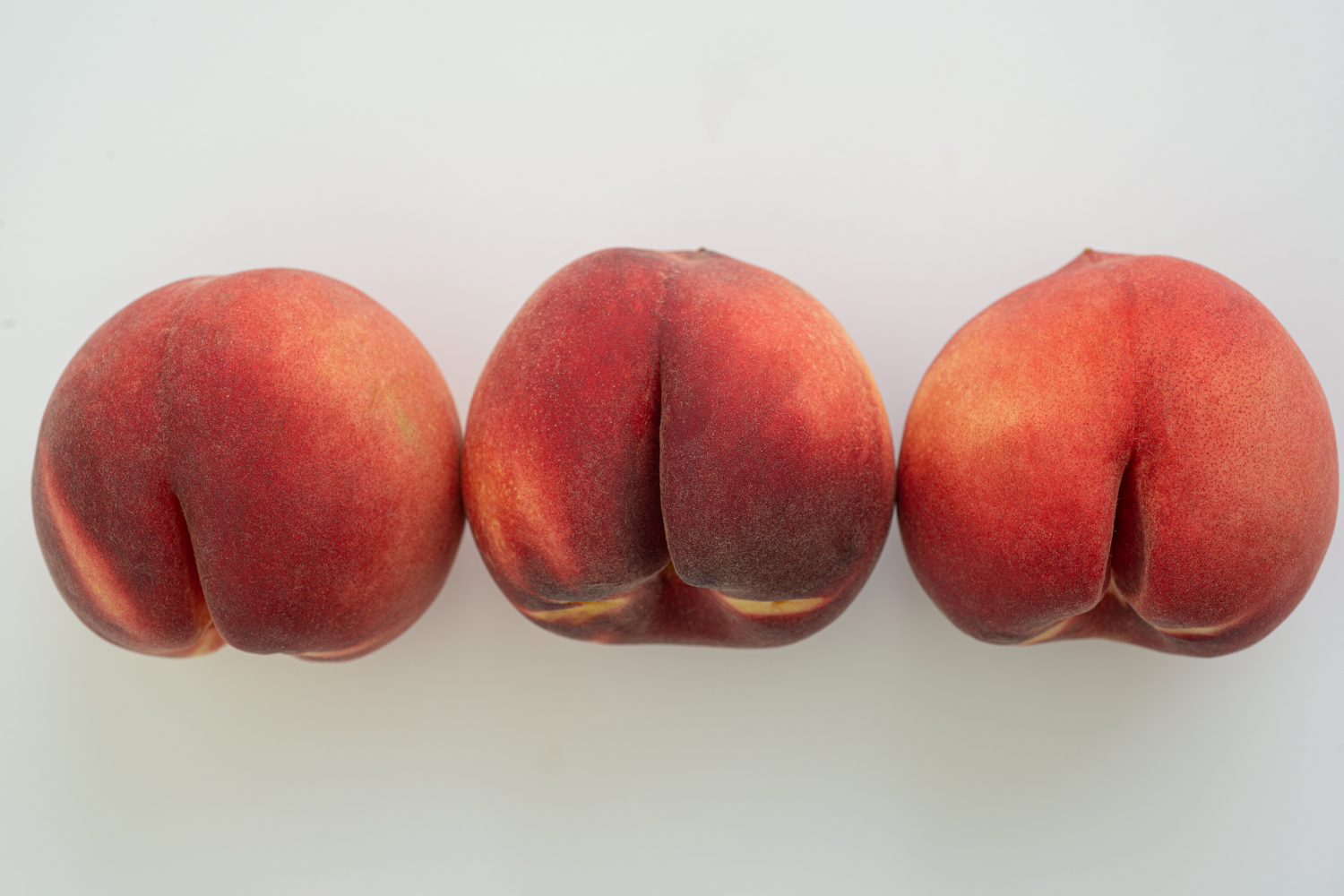 A row of three peaches on a white background. (anal sex concept)